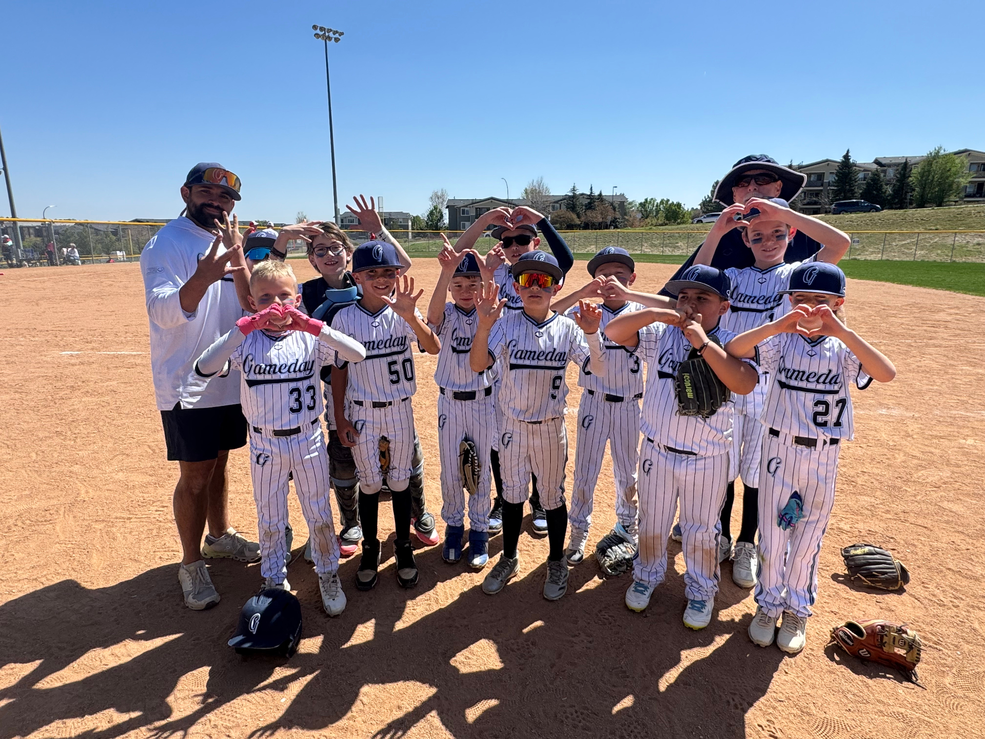 Gameday Kings players and coach forming heart shapes with their hands on the field